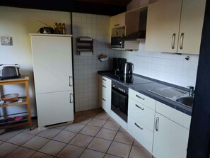 Une cuisine de taille réduite, avec des meubles blancs, un four à micro-ondes, une machine à café et un évier.