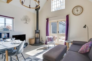 Ein gemütliches Wohnzimmer mit Kamin, Essbereich und einer Couch.