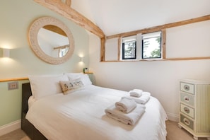 Ein Schlafzimmer mit einem Bett, einem runden Spiegel, einer Kommode und einem Fenster mit Blick.
