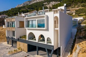 A modern building with a balcony, arched windows, and a view of the surrounding landscape. - Villa Etesia - Three Bedroom Villa, Sleeps 6 (Marušići)