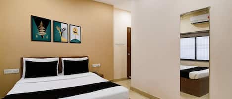A hotel room with a bed, a bedside table, a mirror, and three wall-mounted artworks.