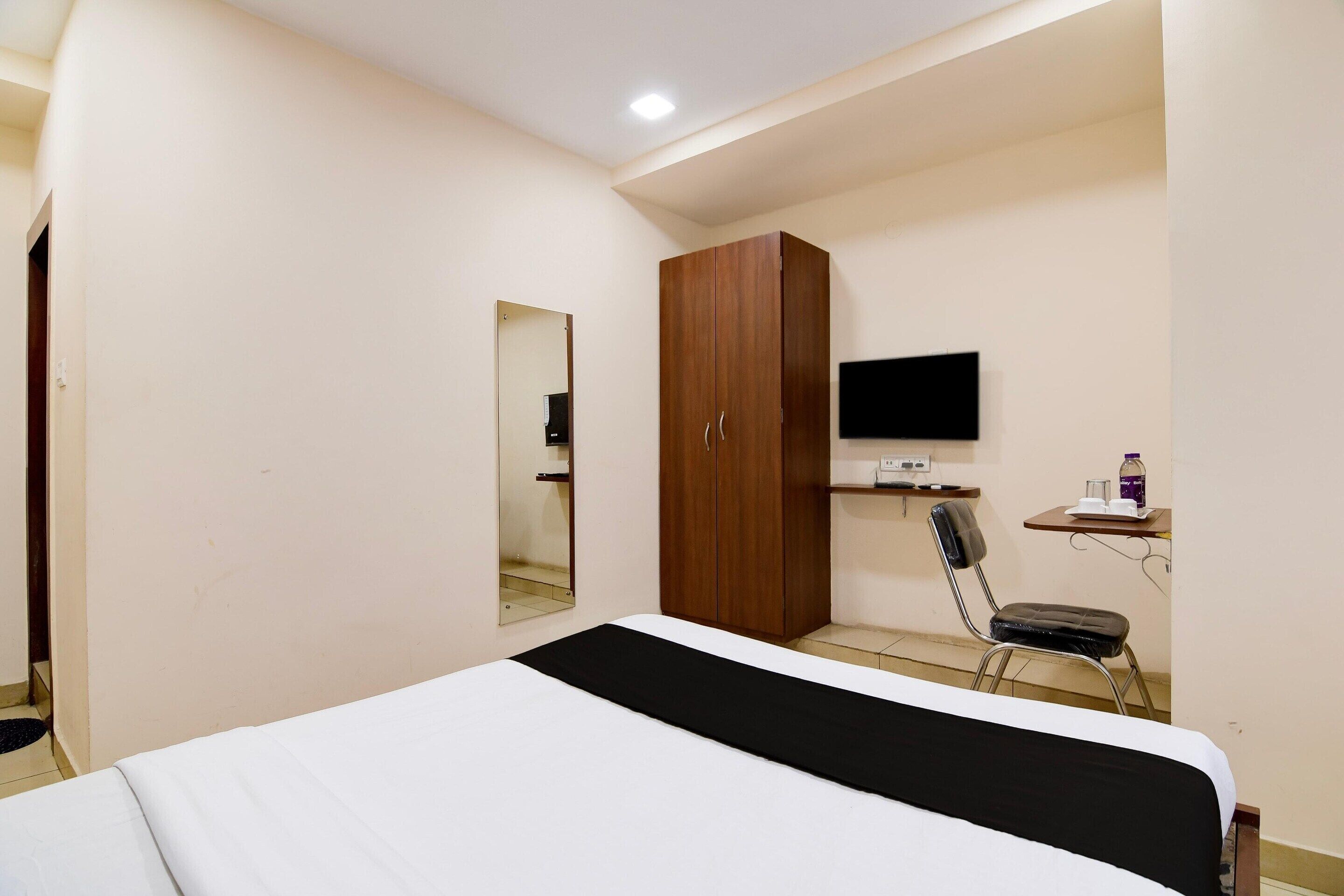 Ein Schlafzimmer mit Bett, Kleiderschrank, Schreibtisch und Stuhl sowie einem Fernseher.