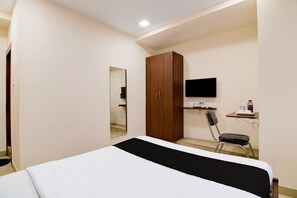 A bedroom with a bed, a wardrobe, a desk with a chair, and a TV. - Deluxe Goukul Recedancy (Barakpur)