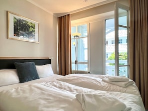 A hotel room with a bed, a window with curtains, a lamp, and a framed picture on the wall. - Hochwertige Ferienwohnung fur 3 im Seepark Sellin (Sellin)