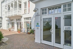A building with a white facade, a balcony with white railings, a glass door entrance, and a sign indicating a restaurant. - Hochwertige Ferienwohnung fur 3 im Seepark Sellin (Sellin)