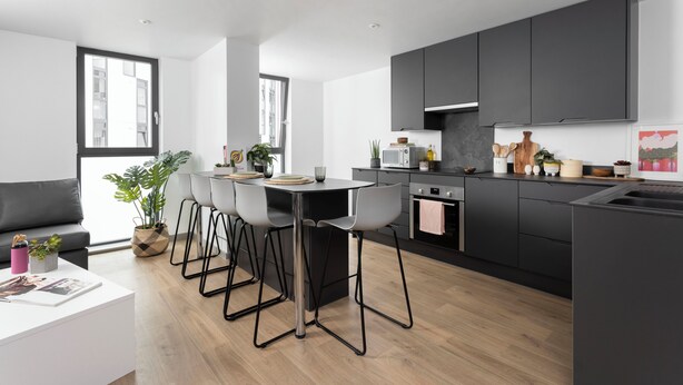 A modern kitchen with a central island, bar stools, and a dining table. - Students Only - Unite Parkway - Manchester (Manchester)