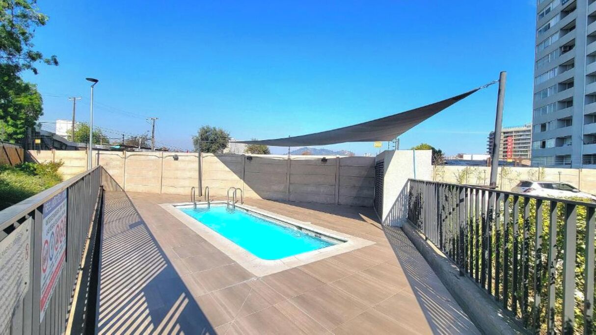 Een dakzwembad met een houten terras, omringd door een metalen hek en een zonnescherm.