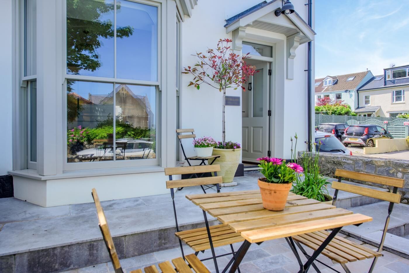 Un bâtiment doté de grandes fenêtres, d’une porte et d’un petit espace extérieur aménagé avec une table et des bancs.