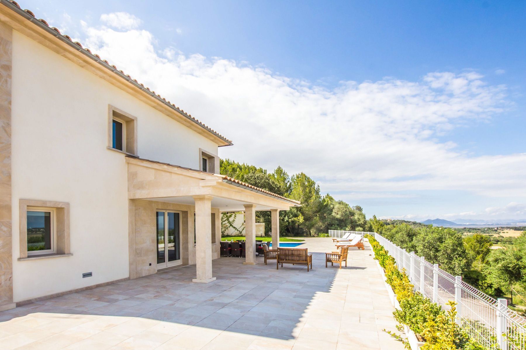 Une maison à deux étages dotée d’un patio couvert, de mobilier d’extérieur et offrant une vue sur le paysage environnant.
