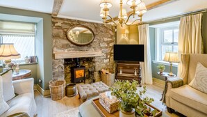 A cozy living room with a stone fireplace, a television, and comfortable seating. - 2 Bed in Glenshee (oc-l37493) (Spittal of Glenshee)