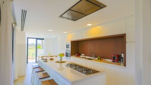 Een moderne keuken met een centraal eiland, barstoelen en een groot raam.