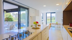 Een moderne keuken met een groot raam, een eethoek met uitzicht, en een klein terras.