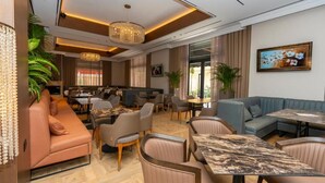 Um lobby moderno de hotel com áreas de estar, espaço para refeições e uma grande tela de televisão.