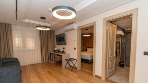 Quarto de hotel moderno com piso de madeira, uma escrivaninha, cama e área de chuveiro.
