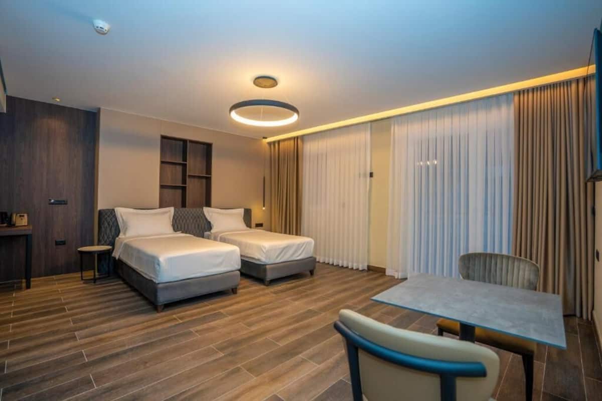 Ett hotellrum med två sängar, ett litet bord och en stol.