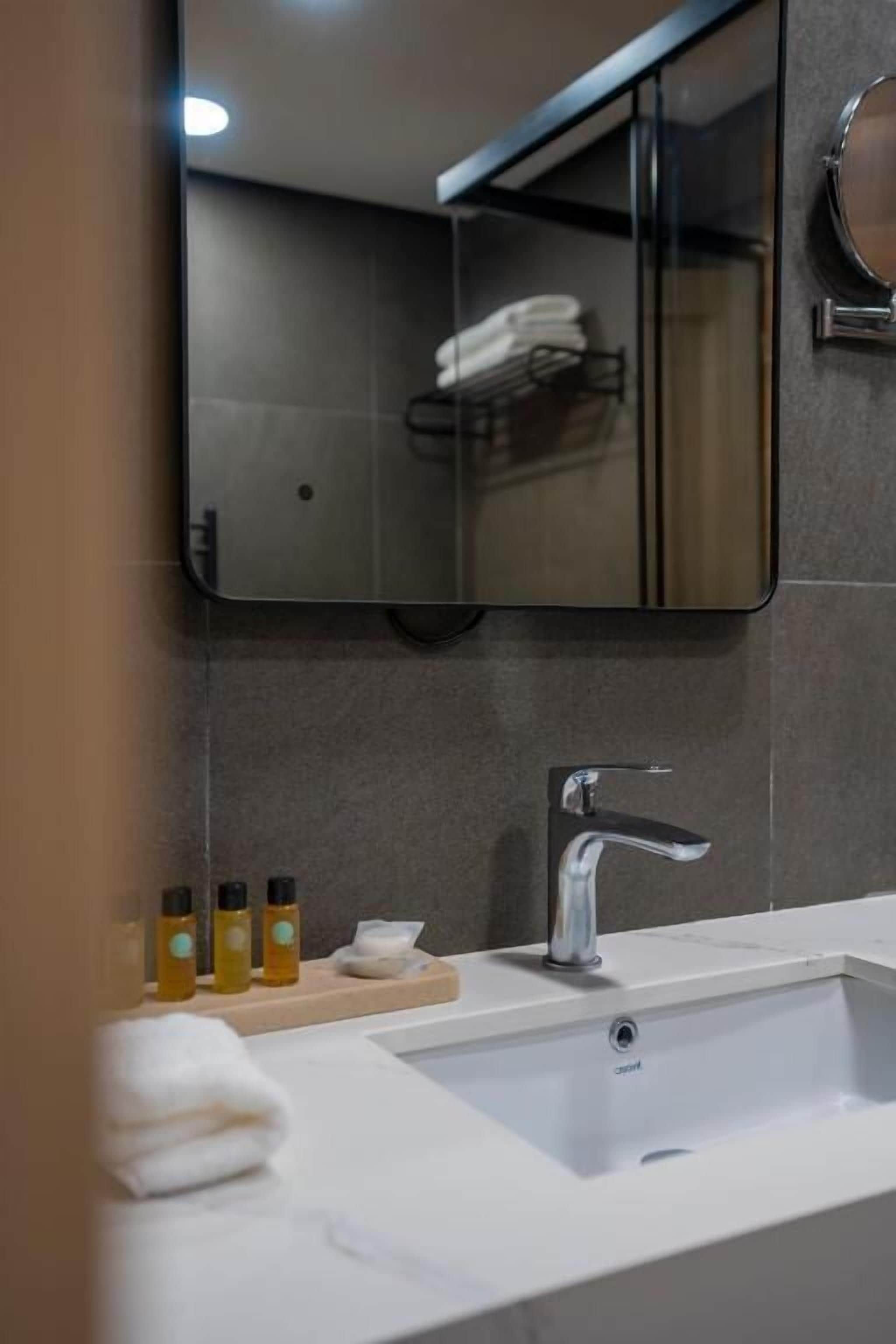 A bathroom with a mirror, sink, and towel rack.