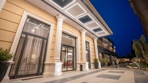 Entrada de hotel com colunas, área externa coberta e escadaria que leva à entrada.