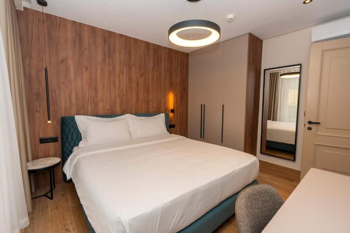 Ett modernt hotellrum med en stor säng, ett litet bord, en spegel och en garderob.