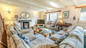 Una sala de estar acogedora con chimenea, asientos cómodos, televisor y comedor.