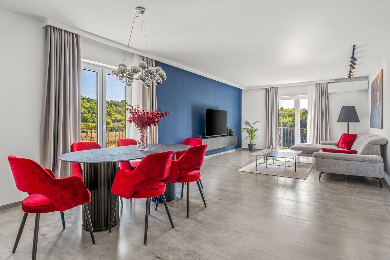 Een moderne woonkamer met een eethoek, een flatscreentelevisie en een balkon met uitzicht.