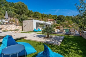 A modern outdoor patio with a pool, seating, and a stone wall. - Villa Vine - Six Bedroom Villa, Sleeps 12 (Donji Vinjani)