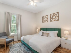 A bedroom with a bed, two bedside tables, a chair, a window with curtains, and a ceiling fan. - 1BR Getaway at Heart of Oaklawn EV Charger (Dallas)