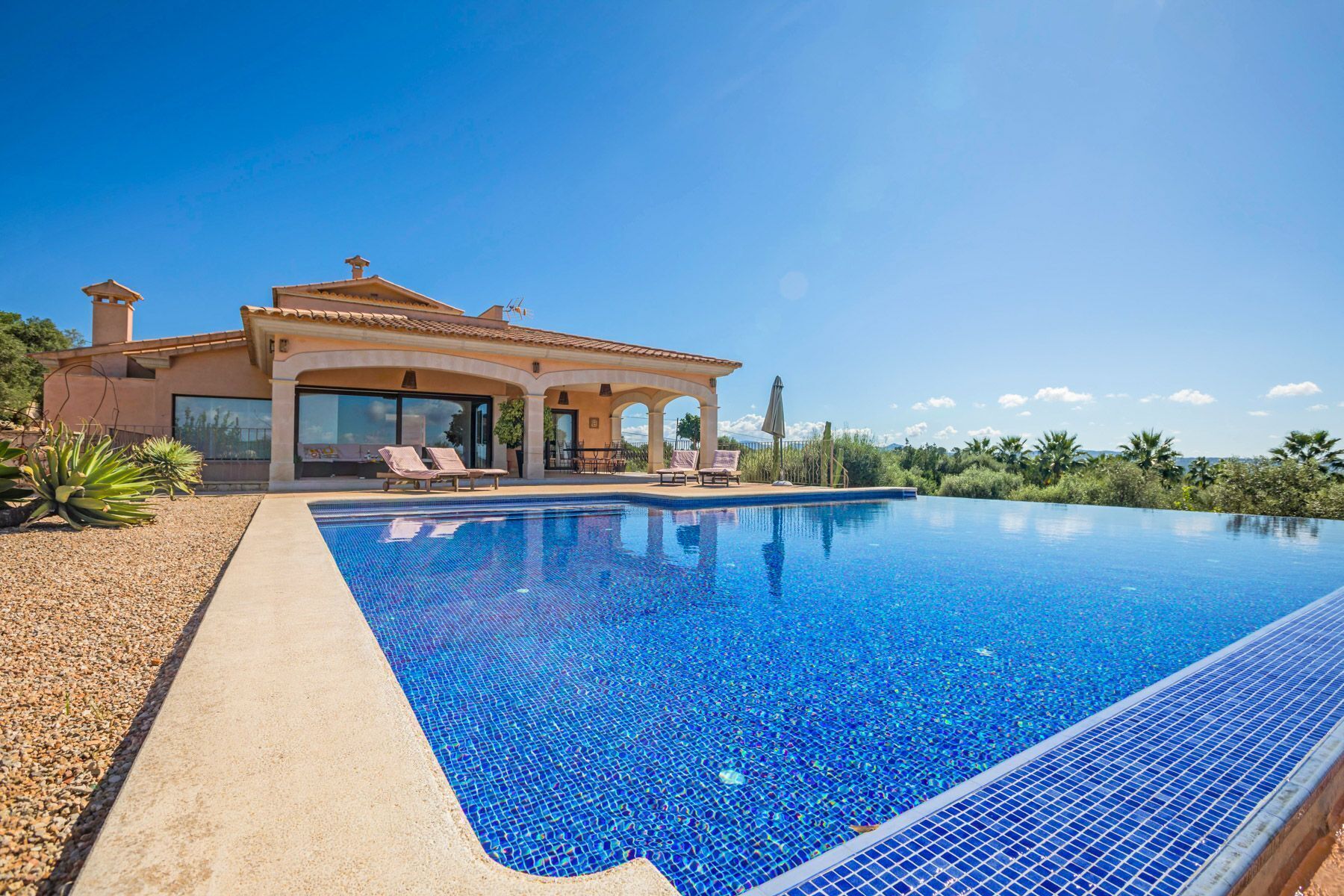 Una casa con piscina, sillas de descanso y una pérgola.