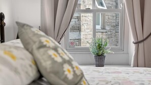A bedroom with a bed, pillows, a window with curtains, and a plant on the windowsill. - 2 Bed in Hawes (oc-c38234) (Hawes)