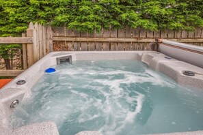 Ein Whirlpool mit Holzzaun und Grünpflanzen im Hintergrund.