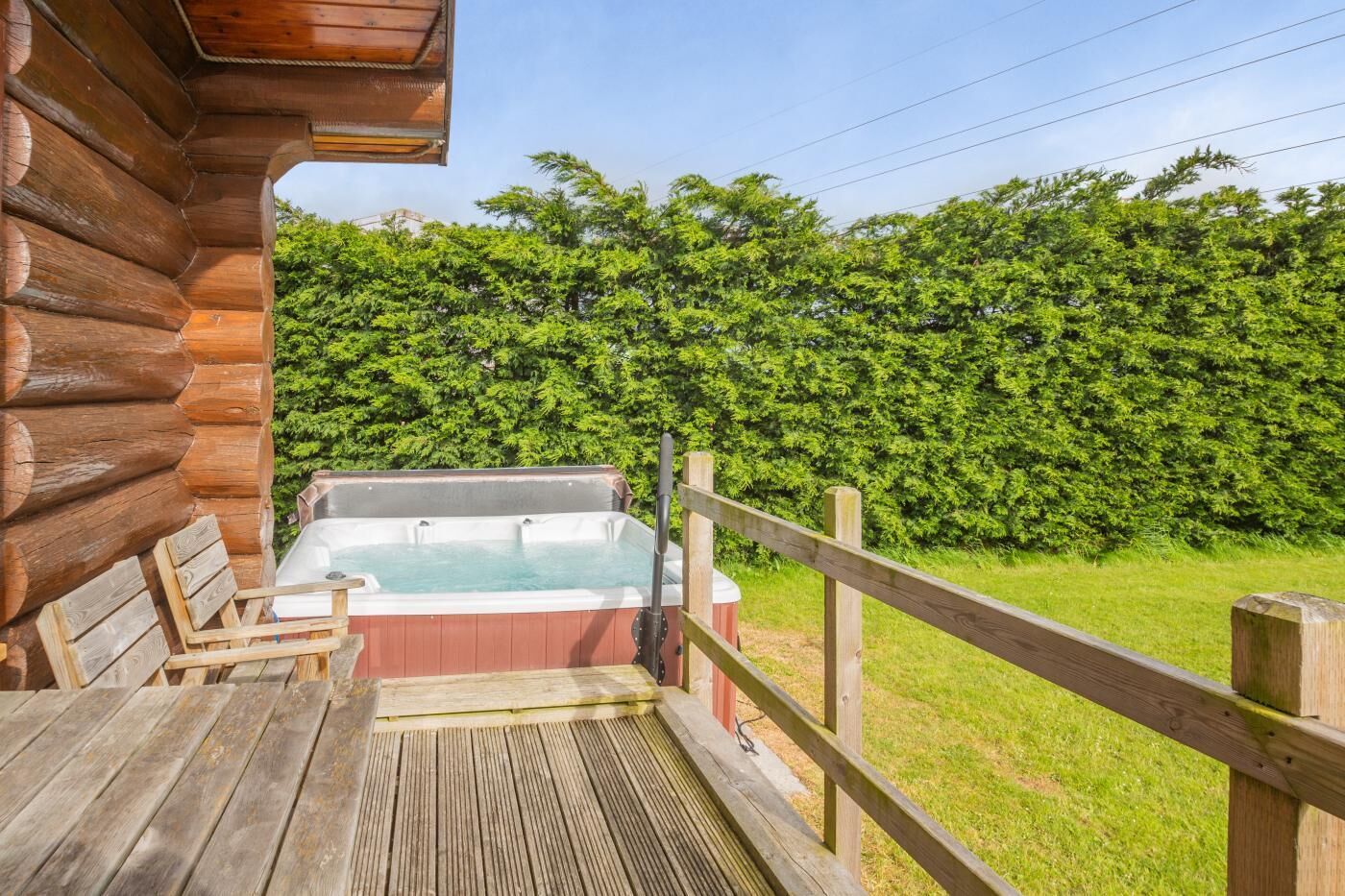 A wooden deck with a hot tub, a wooden table, and a wooden fence.