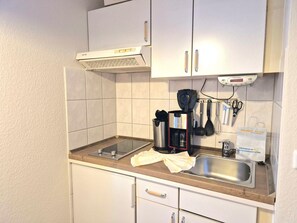A small kitchenette with a stove, sink, and cabinets. - Gemutliches Studio im 2.og in Sellin mit Balkon (Sellin)
