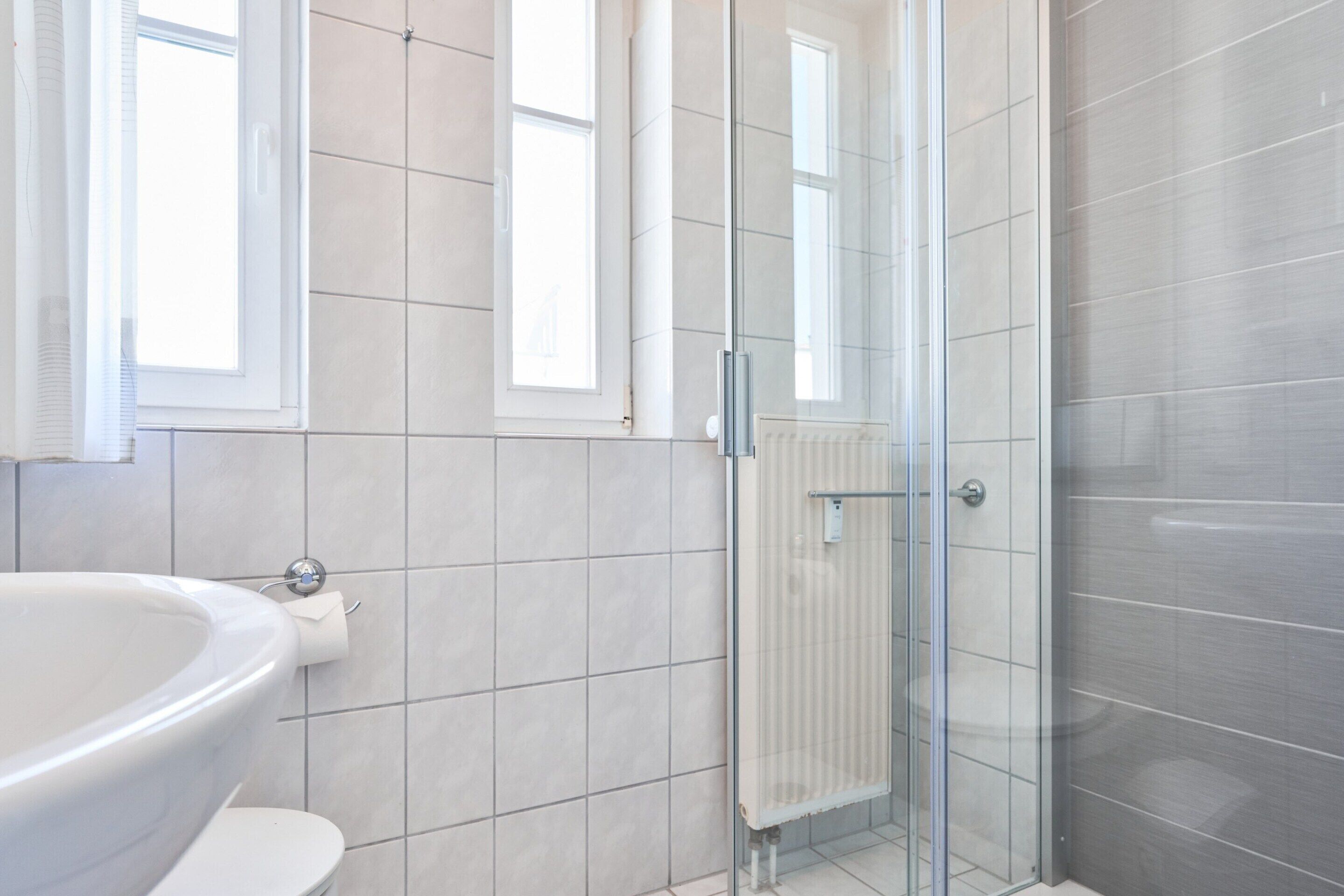 Une salle de bain avec une douche à parois de verre, un lavabo blanc et des toilettes.