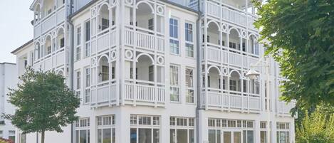 Un immeuble à plusieurs étages doté de balcons, de grandes fenêtres et d’une entrée pavée de briques.