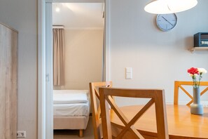 A room with a bed, a wooden chair, a table with a vase, and a clock on the wall. - Geschmackvoll Eingerichtete Ferienwohnung mit Grossem Balkon in Sellin (Sellin)