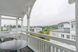 A covered balcony with a table and chairs, overlooking a residential area with houses and greenery. - Geschmackvoll Eingerichtete Ferienwohnung mit Grossem Balkon in Sellin (Sellin)
