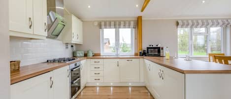 A modern kitchen with white cabinets, a wooden countertop, and a built-in oven.