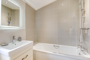 A modern bathroom with a white sink, mirror, and bathtub. - 2 Bed in Athelington (oc-d35071) (Athelington)