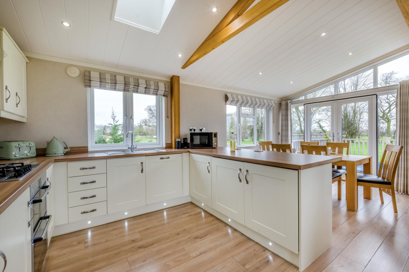 A modern kitchen with white cabinetry, a wooden countertop, and a dining area with a table and chairs.