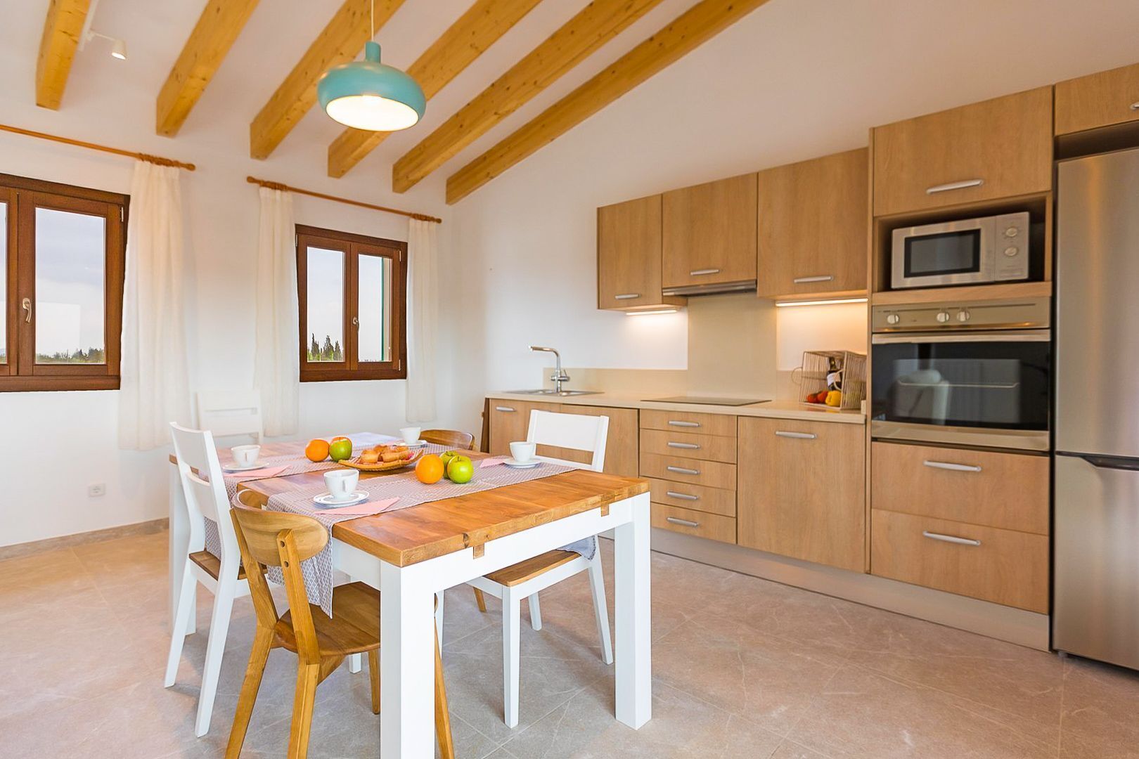 Une cuisine moderne avec des meubles en bois, un réfrigérateur en acier inoxydable et un coin repas comprenant une table et des chaises en bois.