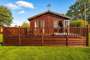 A wooden cabin with a fenced deck, a single door, and a window. - 1 Bed in Athelington (oc-c35073) (Athelington)