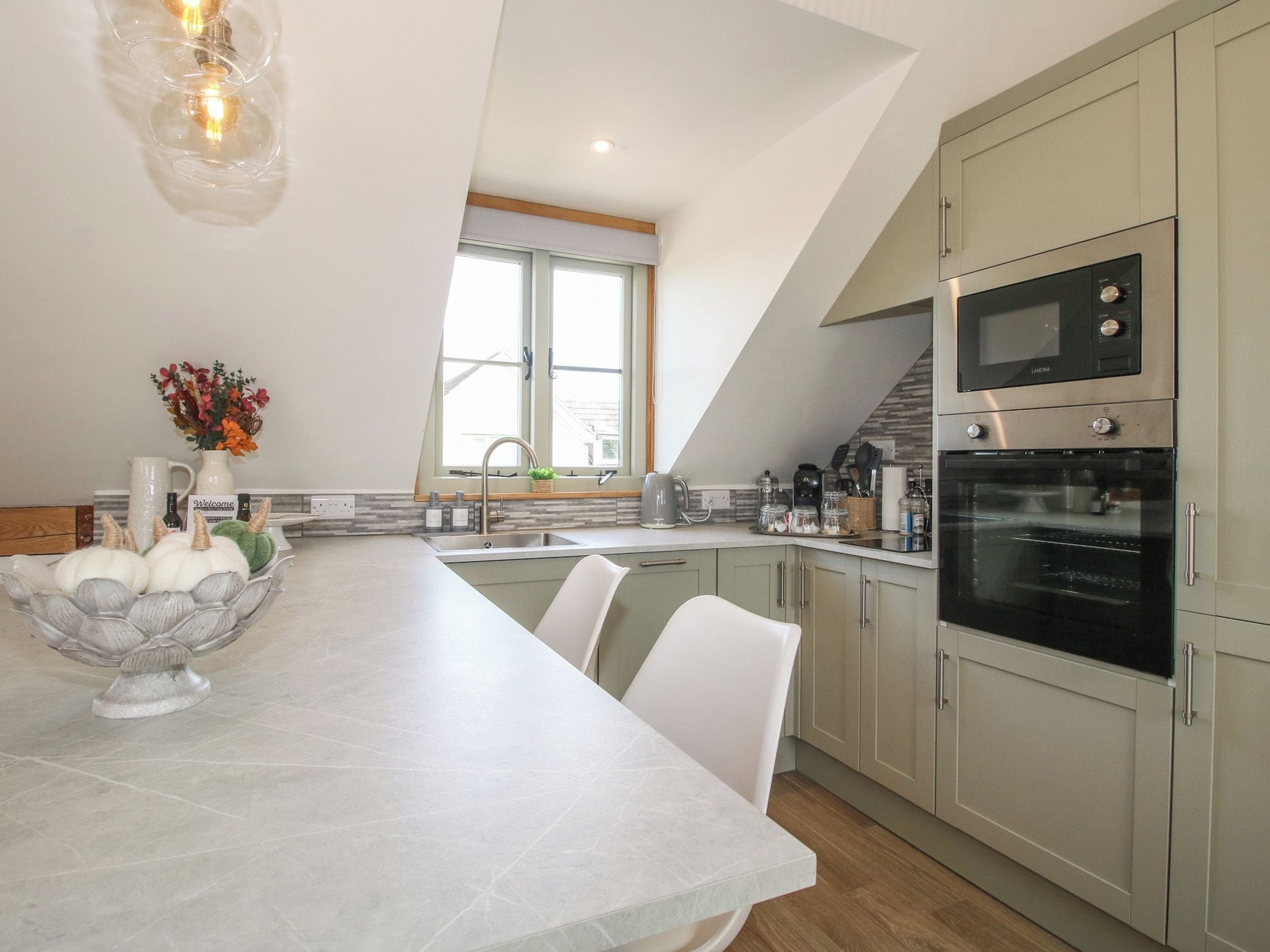 A modern kitchen with a central island, built-in appliances, and a view of the outdoors.