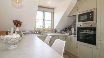 A modern kitchen with a central island, built-in appliances, and a view of the outdoors.