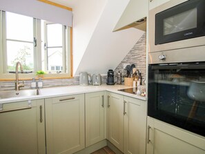 Una cocina con ventana, pileta, estufa y microondas.
