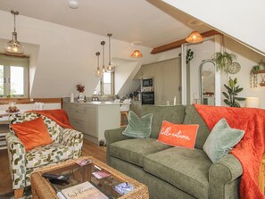 Ein gemütliches Wohnzimmer mit einer Couch, einem Couchtisch und einer Küche im Hintergrund.