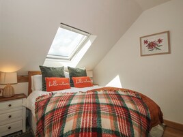 Un dormitorio con tragaluz, colcha escocesa y dos almohadas con el texto 'hello autumn'.