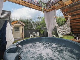 Un jacuzzi con cubierta de madera, una hamaca y una pequeña mesa con sillas.
