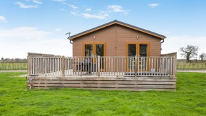 Una baita in legno con una veranda, ampie finestre e un portico recintato.