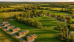 Un paysage rural avec une rangée de maisons, un ciel dégagé et de vastes champs verdoyants.