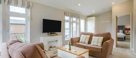 Una sala de estar con sofá, mesa de centro, televisor de pantalla plana y chimenea.
