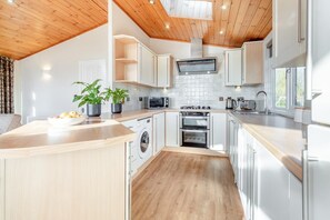 Eine moderne Küche mit Holzbalkendecke, Edelstahlgeräten und einer zentralen Kochinsel.